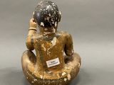 statue of a man sitting in a lotus position with a label on his chest