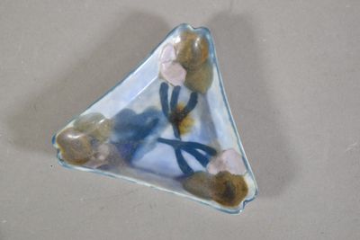 un petit objet en verre en forme de triangle orné de fleurs