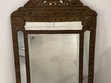 un miroir ancien avec un cadre en bois et un motif décoratif dans la partie supérieure