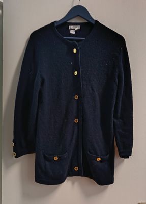 un cardigan bleu marine à boutons dorés, suspendu à un cintre