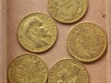 six types différents de pièces d'or dans une boîte posée sur une table