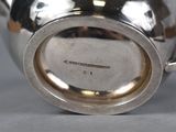 a silver tea pot with a handle on a table