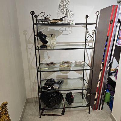 une étagère en verre sur laquelle sont posés divers objets, dans une pièce