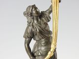 an antique bronze statue of a woman holding a torch in her hand