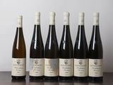 six bottles of wine are lined up on a wooden table