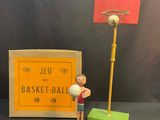 figurine représentant un homme tenant un ballon de basket à côté d'une boîte de ballons de basket