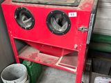 un poêle rouge posé dans un garage, à côté d'une poubelle