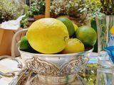 a silver bowl filled with lemons and limes on a table