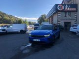 La voiture bleue est garée devant un immeuble sur lequel est accrochée une pancarte indiquant uniquement