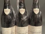 three bottles of wine wrapped in plastic sitting on top of a table