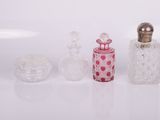 three glass bottles and a small glass container on a white surface