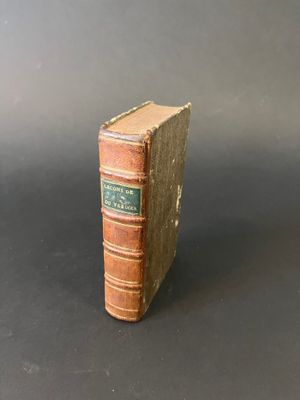 an old book sitting on top of a black table next to a gray wall
