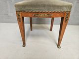 a small wooden stool with a velvet seat on it
