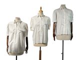trois mannequins vêtus de chemises blanches, exposés sur un présentoir en bois