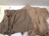 two pairs of tan and brown shorts laying on a white surface