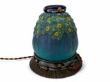 un vase bleu orné de fleurs jaunes, posé sur un socle