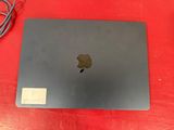 an apple macbook is sitting on a red table with a charger attached to it