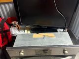 a television sitting on top of a stove next to a bag