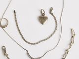 un assortiment de bijoux en argent comprenant un pendentif en forme de cœur, une chaîne et une paire de boucles d'oreilles