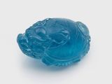 une image représentant une figurine en verre bleue en forme de poisson posée sur une surface blanche