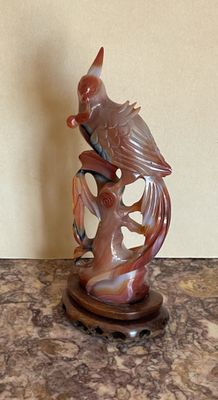 une figurine représentant un oiseau perché sur une branche d'arbre
