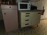 un micro-ondes posé sur un meuble, à côté d'un réfrigérateur