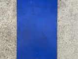a blue sign on the sidewalk that is on the ground