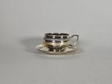 une tasse et une soucoupe en argent, avec une soucoupe posée sur une autre soucoupe