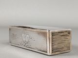 un étui à cigarettes en argent posé sur une surface blanche