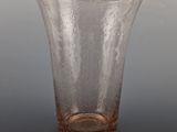 a clear glass vase with a brown base on a table