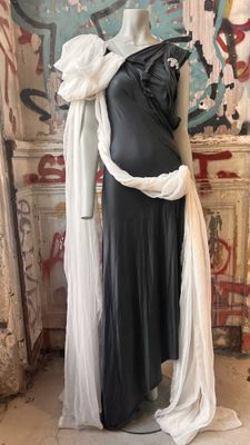 a mannequin dressed in a black dress and white scarf