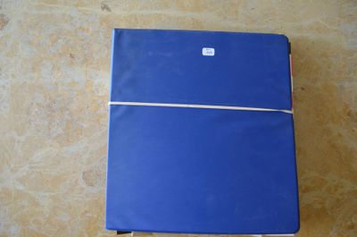 un cahier bleu posé par terre, sur lequel est accrochée une étiquette