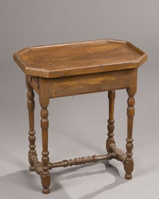 an old wooden table with turned legs and a wooden tray on top