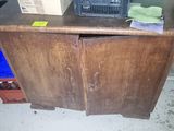 a wooden cabinet with a microwave on top of it