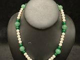 a green and white beaded necklace on a mannequin