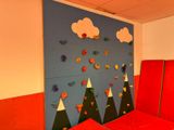 a red bed in a room with a blue wall and mountains on the wall