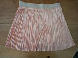 pink and white pleated skirt on a wooden table on a wooden floor