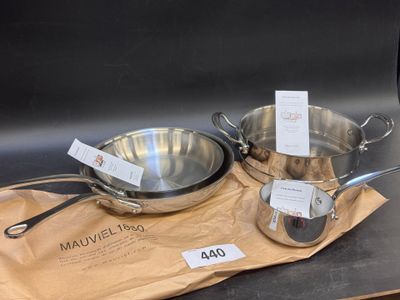deux casseroles et poêles posées sur un sac, sur une table