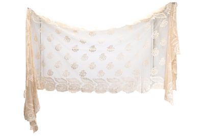 une écharpe en dentelle beige et blanche accrochée à un mur blanc