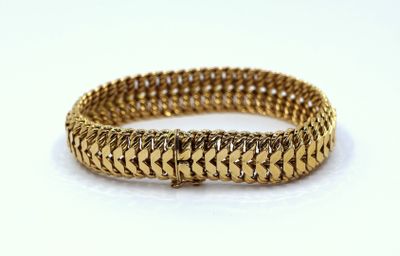 a close up of a gold bracelet on a white surface