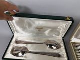 two silver spoons and a spoon in a case