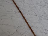 un bâton en bois posé sur une surface en marbre, muni d'un manche en métal