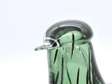 a green glass bird sitting on top of a table