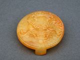 une image représentant un bouton en jade jaune sculpté orné d'un lion