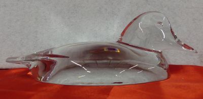 a glass duck sitting on top of an orange table cloth