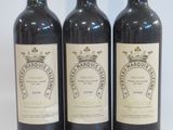 three bottles of wine are lined up on a white surface