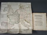 an old map of europe with a book open on a table