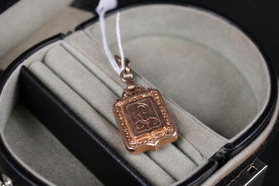 une petite médaille d'or dans un écrin posé sur une surface noire