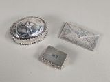 trois bijoux en argent posés sur une surface blanche