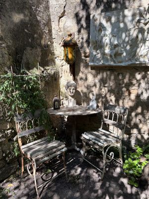 a small table and two chairs in the shade of a tree